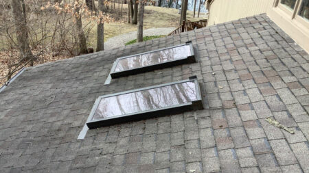 Before skylights Canton roof replacement: Damaged roof with two skylights, illustrating the need for Bruce's roofing services in Canton. 149 characters