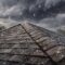 Spring storm roof inspection: Hail falls on a shingled roof during a spring storm, emphasizing the need for roof inspection before storm season hits hard.